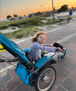 Meret sitzt in ihrem neuen Jogger, im Hintergrund sieht man Sand und Strand